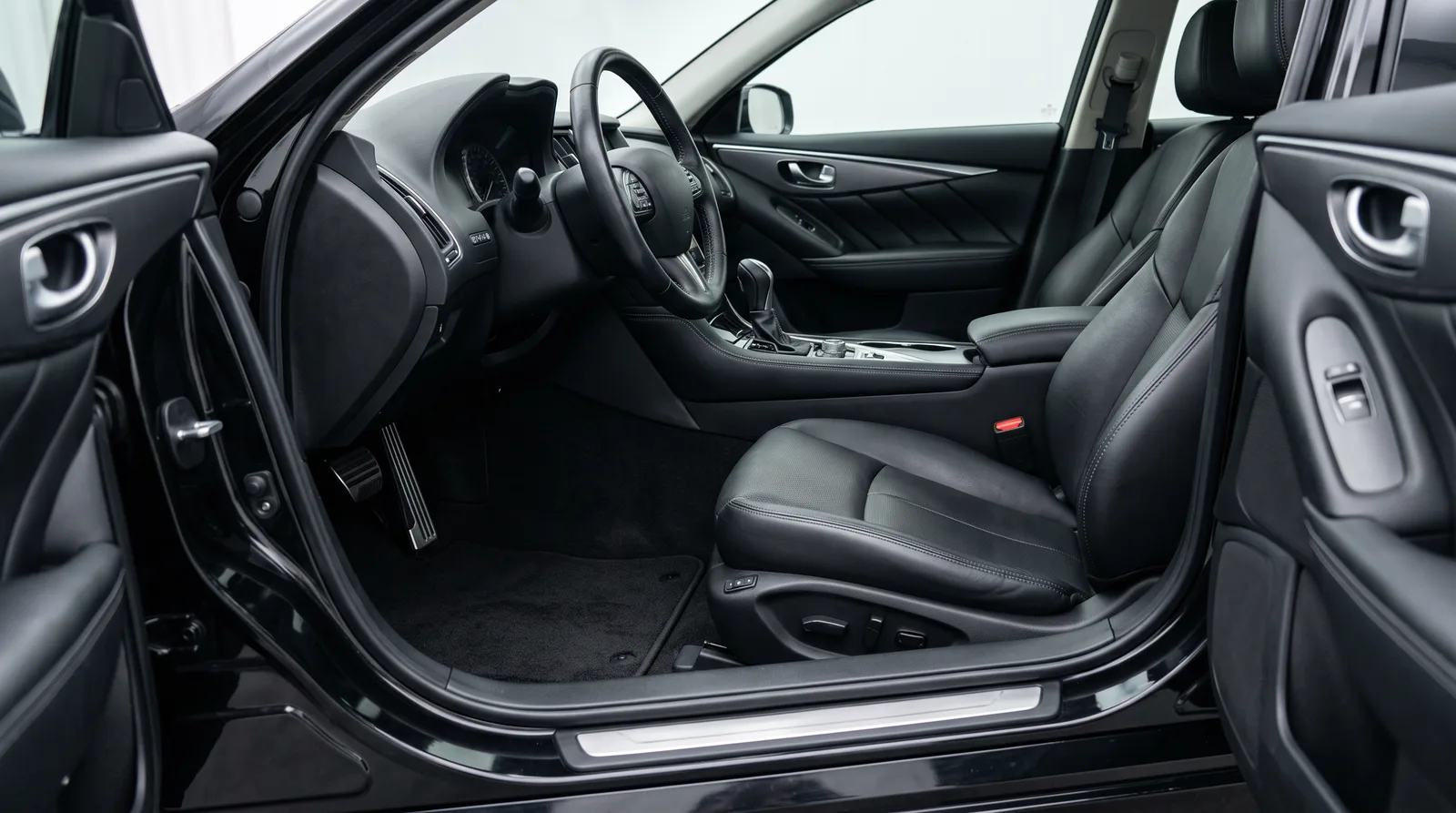 Freshly detailed car interior with clean black leather seats and carpet, from the driver door sill