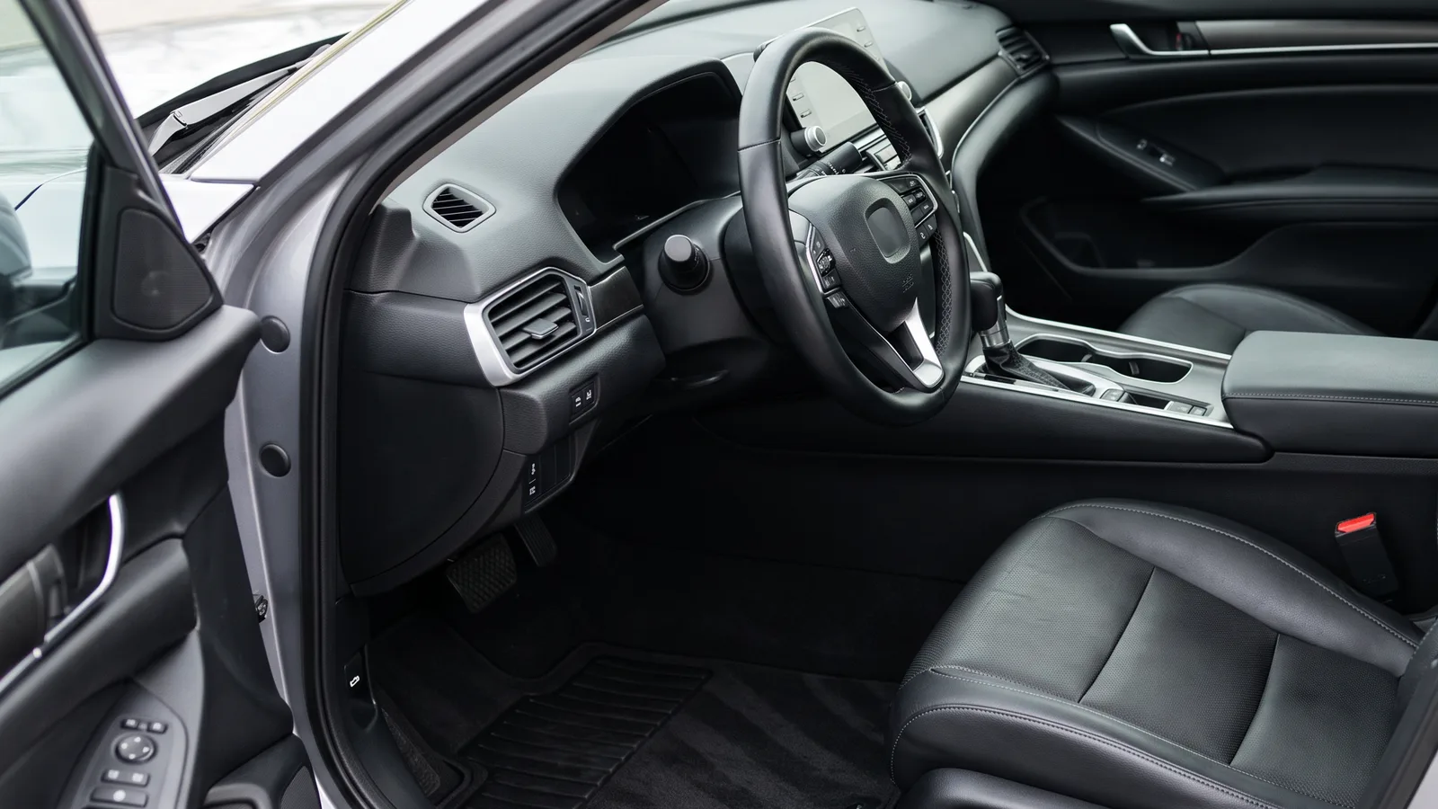 Freshly detailed car interior with clean black leather seats, vacuumed carpet and clean floor mats, ready for pickup after a detailing appointment