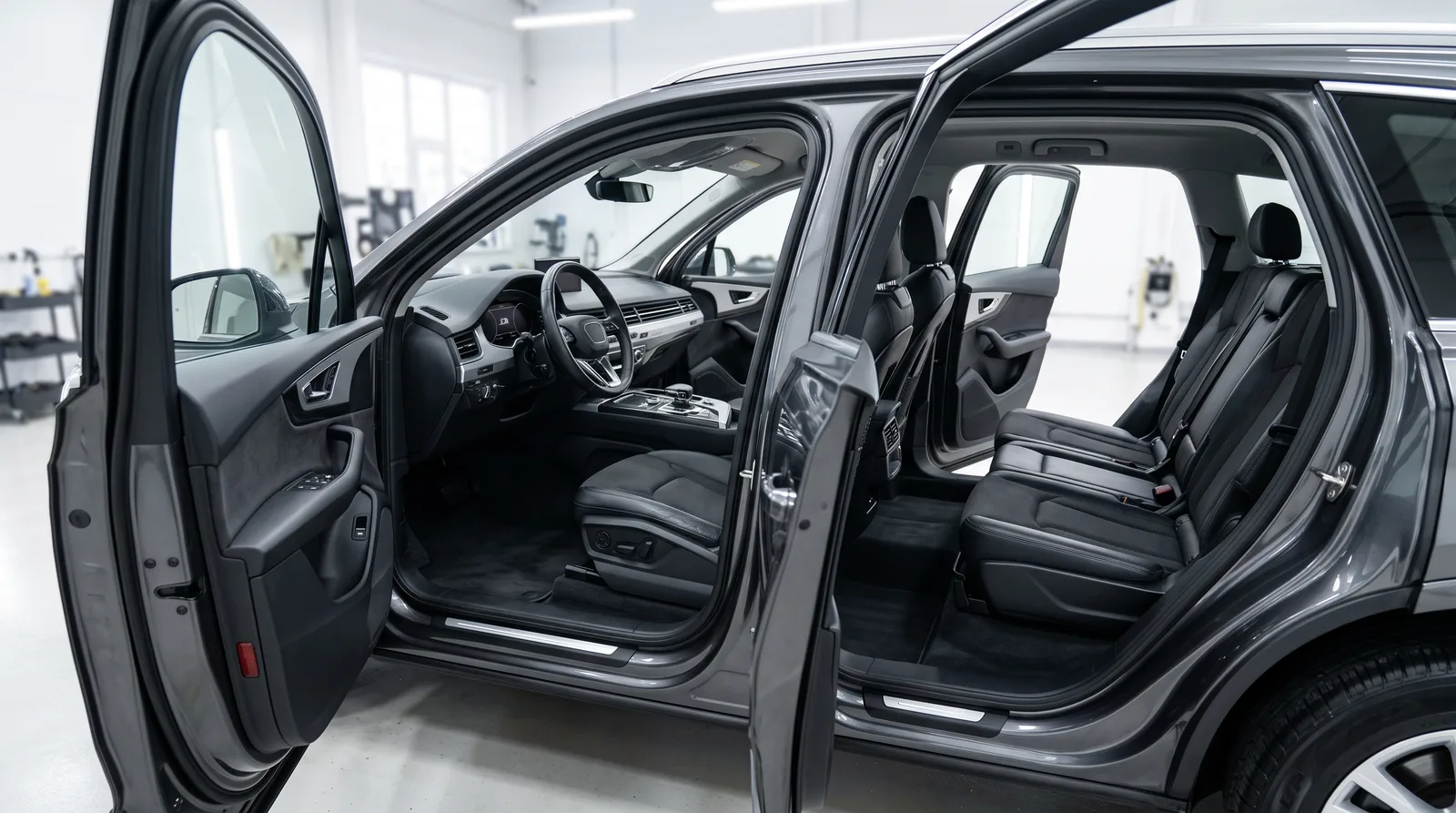 Clean SUV interior with all doors open to air out in a bright indoor detailing studio