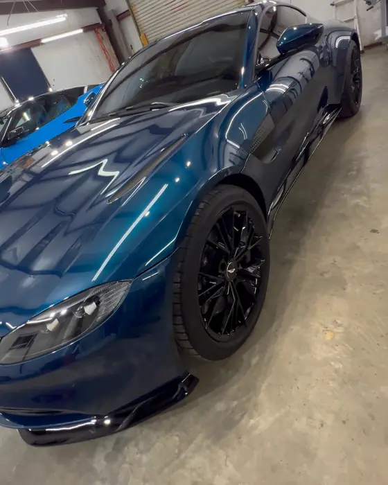 A teal Aston Martin Vantage in our Opelika shop after ceramic coating, front wheel and fender in the shop lights
