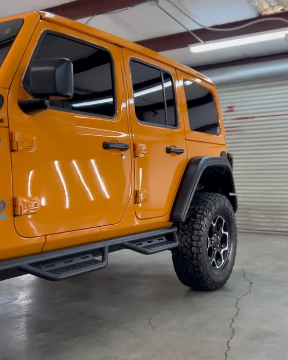A lifted orange Jeep Wrangler Rubicon 4xe in our shop after ceramic coating