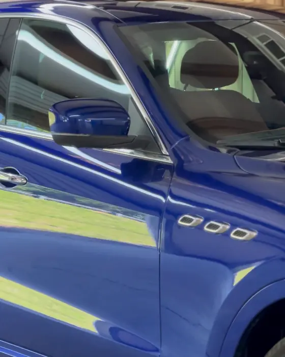 A deep blue Maserati Levante side reflecting the shop lights after ceramic coating